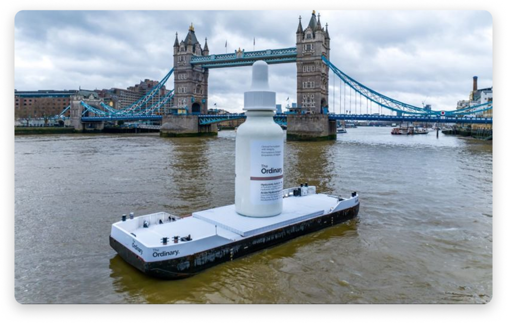 Large replica The Ordinary skincare bottle displayed on a floating platform in the River Thames near Tower Bridge as part of a brand publicity stunt.